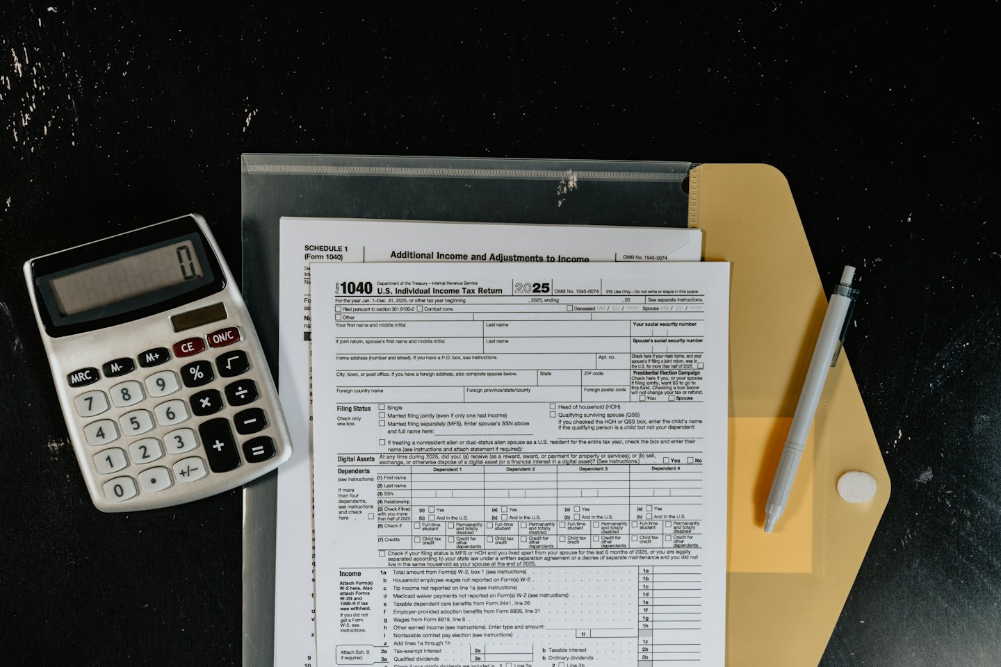 U.S. tax forms, calculator, and pen on a desk.